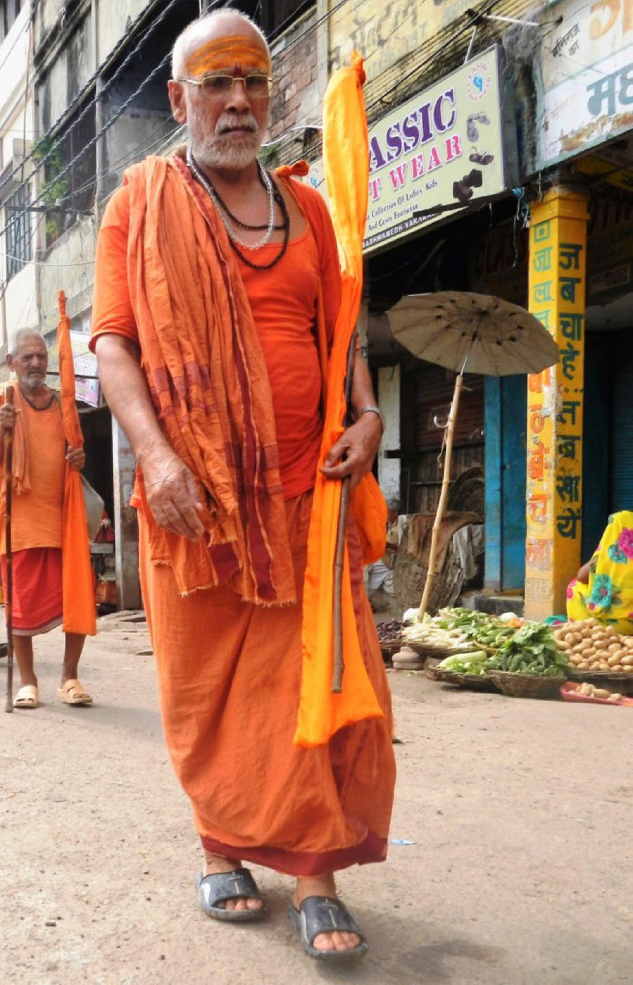 Pilger in der Altstadt von Varanasi mittags -Ein Sadhu werden: Die Prozesse und Rituale, ein Sadhu zu werden, variieren mit Sekte; in fast allen Sekten wird ein Sadhu von einem Guru initiiert, der dem Eingeweihten einen neuen Namen verleiht, sowie ein Man