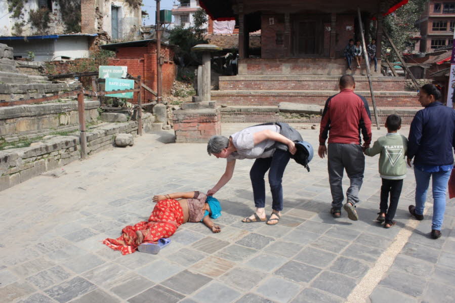 Eine Touristin am Durbar Spuare - Eine Touristin erweist sich als guter Mensch, denn sie deckt eine Schlafende auf dem Durbar Square zu. Sie hat wohl nicht bedacht, dass der Tag warm ist..