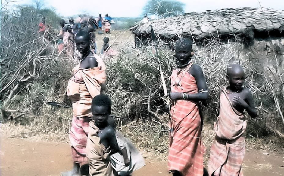 Ein Besuch in einem Massai-Dorf  in Kenia 1980:Die Hütten (Boma) der Massai sind aus getrocknetem Kuhdung, Lehm und einzelnen Holzpfosten hergestellt. In den Hütten, in denen auch Kleintiere schlafen, brennt ständig ein kleines Feuer, das am Tag zum Koche